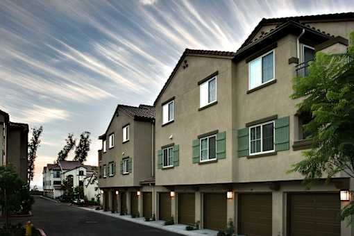 A row of houses with green shutters on the windows.