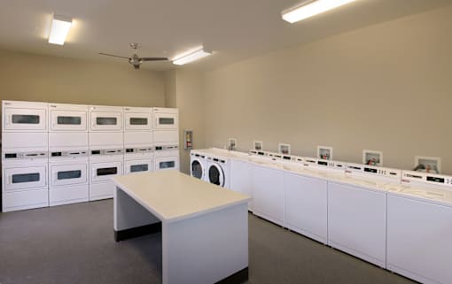 A room with a table and a wall of washing machines.