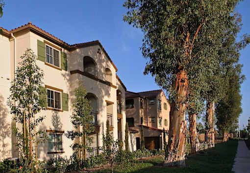 A row of houses with trees in front of them.