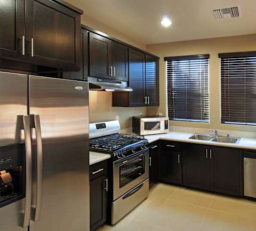A modern kitchen with black cabinets and stainless steel appliances.