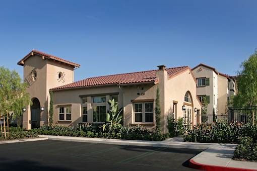 A building with a red tile roof and a parking lot in front.