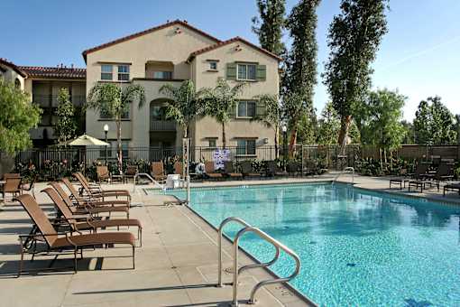 A swimming pool with sun loungers and a building in the background.