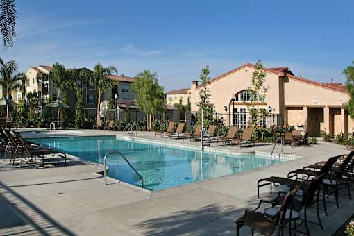 A pool surrounded by chairs and trees.