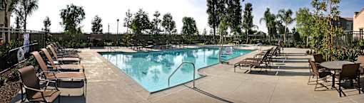 A large outdoor swimming pool surrounded by chairs and trees.