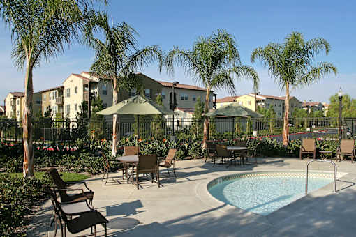 A pool surrounded by chairs and trees in front of apartment buildings.