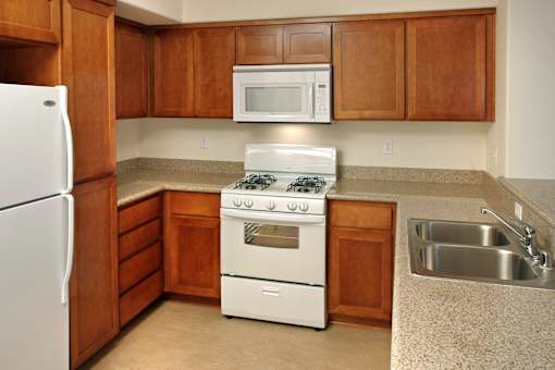 A kitchen with a white refrigerator, white stove, and brown cabinets.