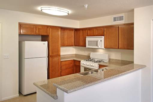 A kitchen with a white refrigerator, brown cabinets, and a white stove top oven.