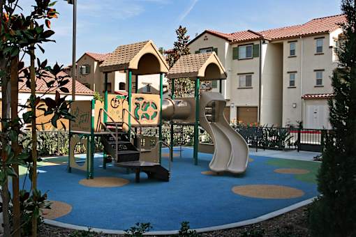 A playground with a slide, swings, and a seesaw.