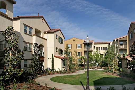 A building with a red tile roof and a green lawn in front.