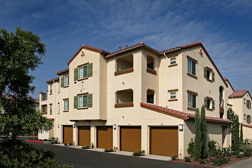 A large house with a red tile roof and tan walls.