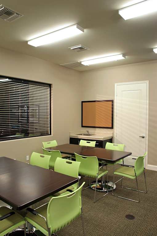 A conference room with a long table and green chairs.