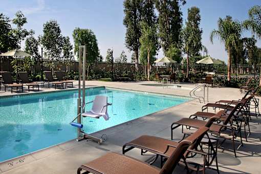 A pool with a ladder and chairs around it.