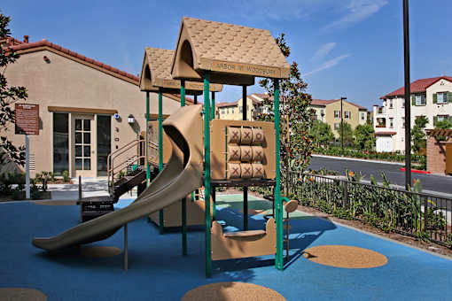 A playground with a slide and a brown roofed structure.