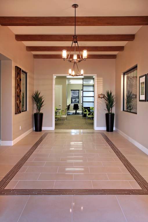 A hallway with a tiled floor and a chandelier hanging from the ceiling.