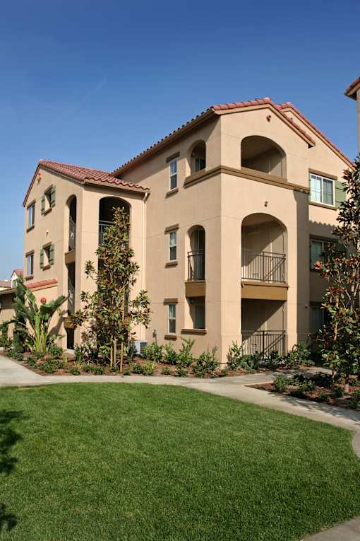 A beige building with a red tile roof and balconies.