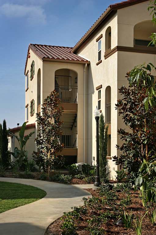 A white house with a red tile roof and a balcony.