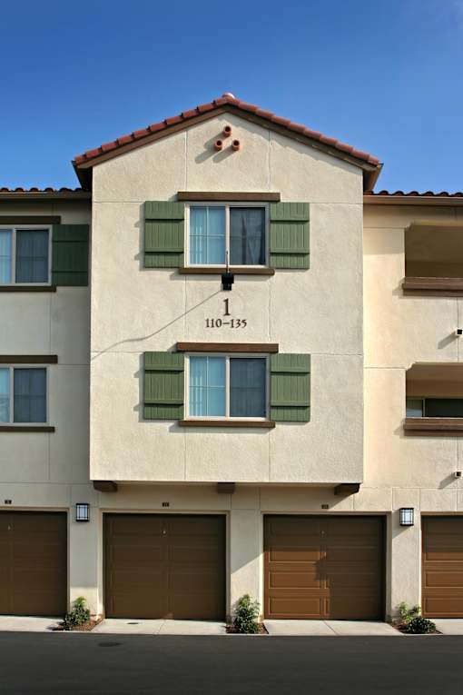 A two-story building with a tan facade and green shutters.