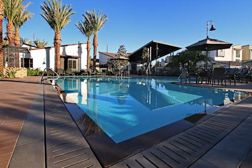 A pool surrounded by palm trees and a patio area.