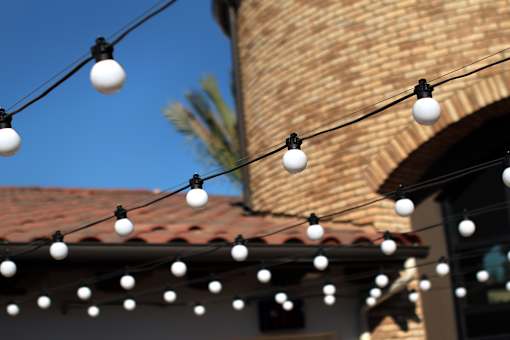A string of white lights hangs in front of a building with a red tile roof.