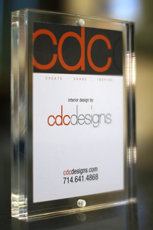 A framed sign with the letters CDC on it, with the website and phone number for CDC Designs underneath.