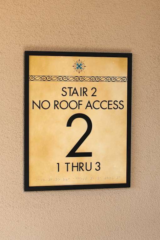 A sign on a wall that says "Stair 2 No Roof Access 2 1 Thru 3".