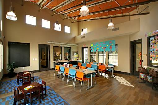 A room with tables and chairs and a blackboard on the wall.