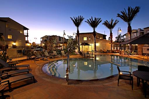 A pool surrounded by palm trees and lounge chairs.