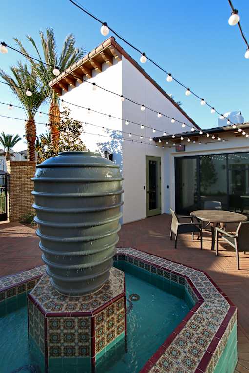 A pool with a waterfall and a table and chairs outside a house.