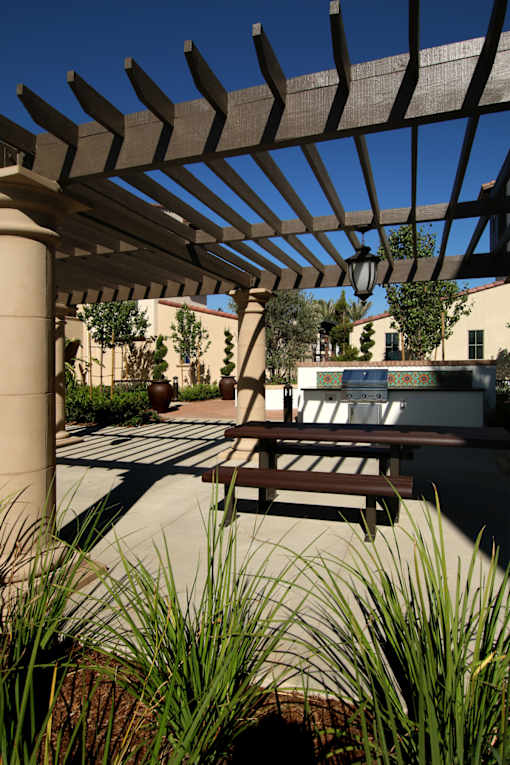 A wooden pergola with a metal roof is over a patio with a table and chairs.