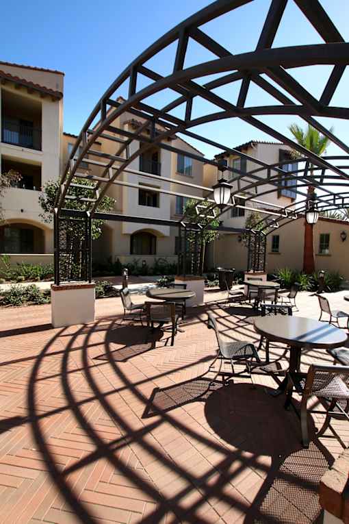 A patio with tables and chairs under a metal awning.