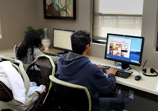 A man and a woman are working on computers in an office setting.