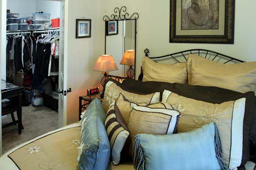A bedroom with a bed, a mirror, and a lamp.