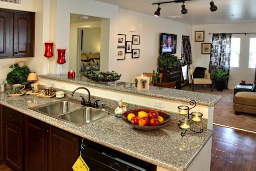 A kitchen with a granite countertop and a bowl of fruit on it.