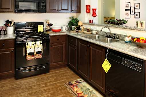 A kitchen with a black stove and wooden cabinets.