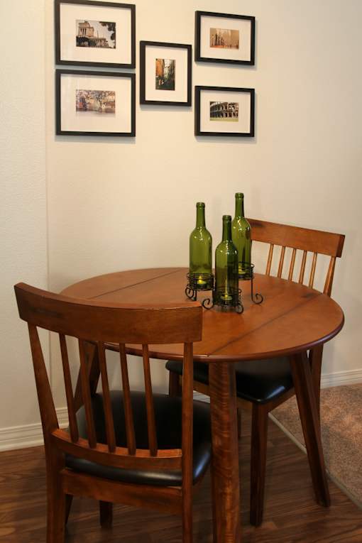 A wooden table with two chairs and three bottles on it.