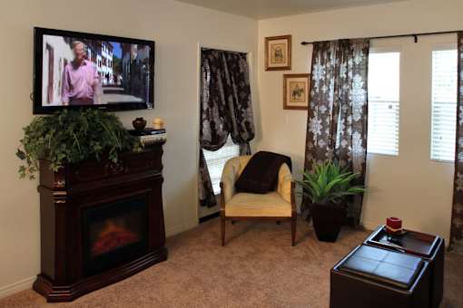 A living room with a fireplace, chair, and a television.