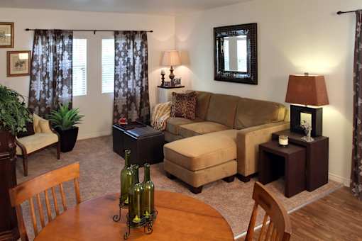 A living room with a brown couch, a wooden table, and a chair.