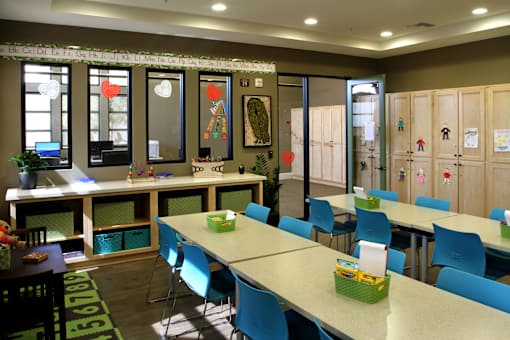 A room with tables and chairs and a wall with drawings on it.