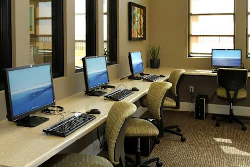 A row of computers are on desks in an office.