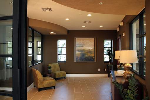 A living room with a painting on the wall and a lamp on the side table.
