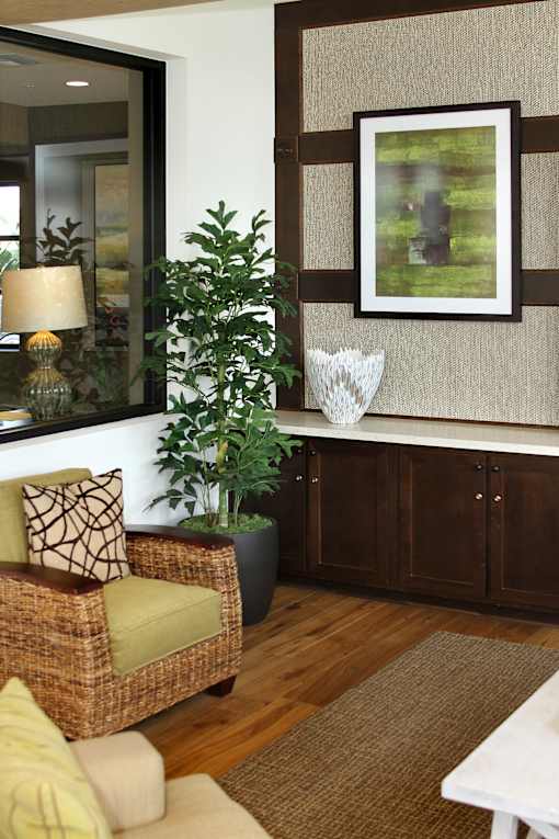 A living room with a chair, a plant, a table, and a picture on the wall.