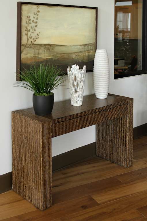 A black vase sits on a wooden table next to a white vase.