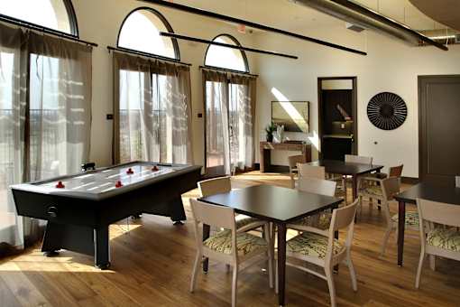 A pool table is in the middle of a room with a dining table and chairs.