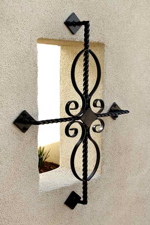 A black wrought iron window frame with a decorative design.