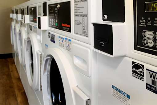 A row of white washing machines in a public laundromat.