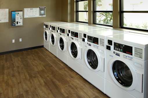 A row of white front load washing machines in a laundromat.