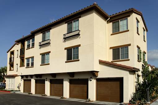 A two-story building with a beige facade and brown garage doors.