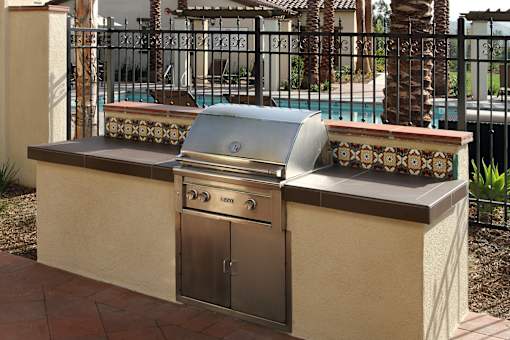 A built in stainless steel grill is on a tan wall.