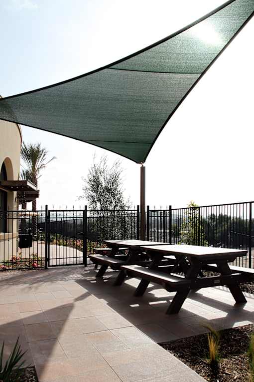 A picnic table is under a green shade sail.