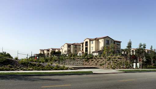 A row of houses on a hillside with a street in front.
